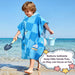 Child wearing nautical hooded poncho towel walking on beach with bucket and shovel, snap button detail shown