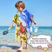 Child wearing crab pattern hooded poncho towel walking on beach with bucket and shovel, button detail shown